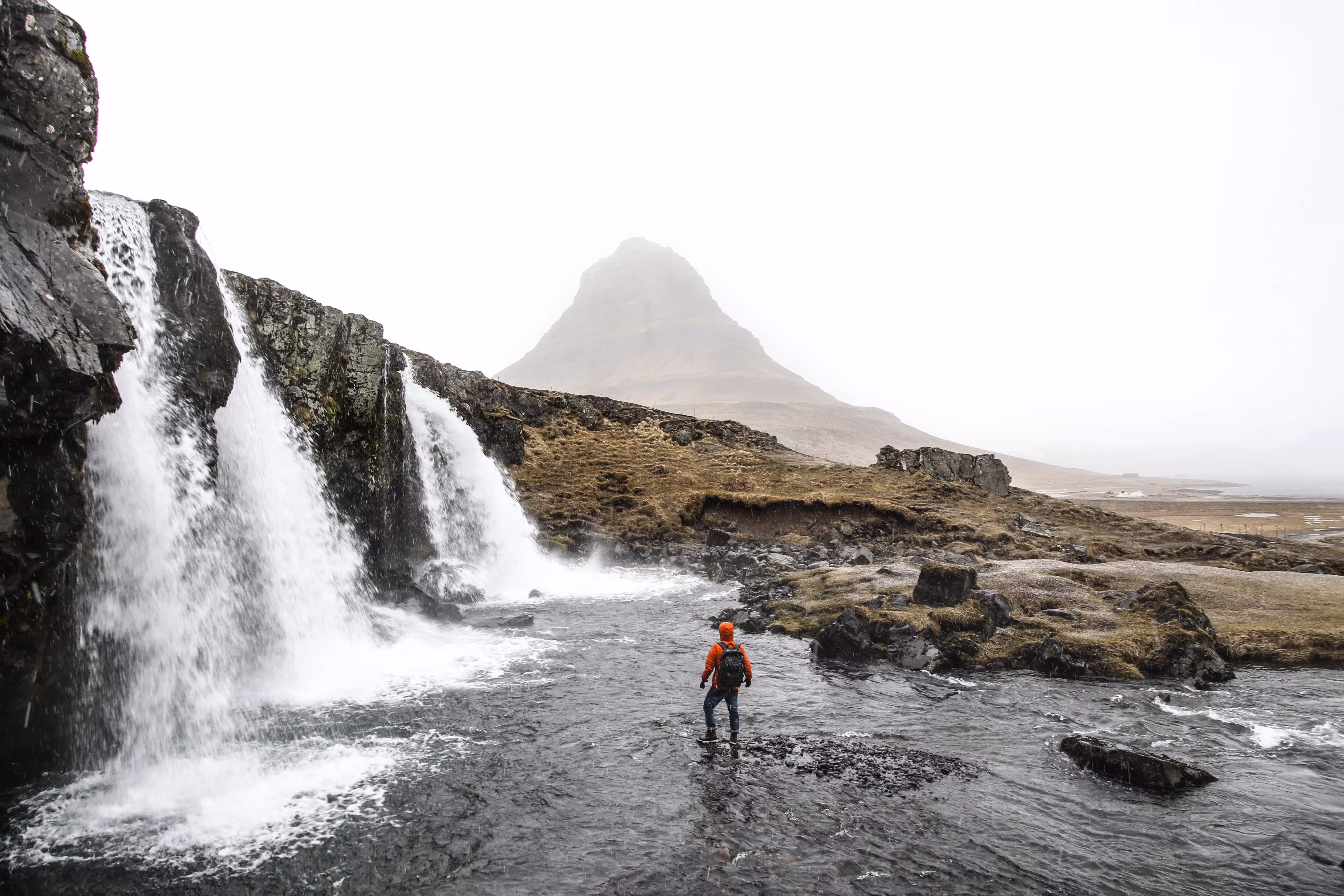 Person standing near waterfall in Iceland