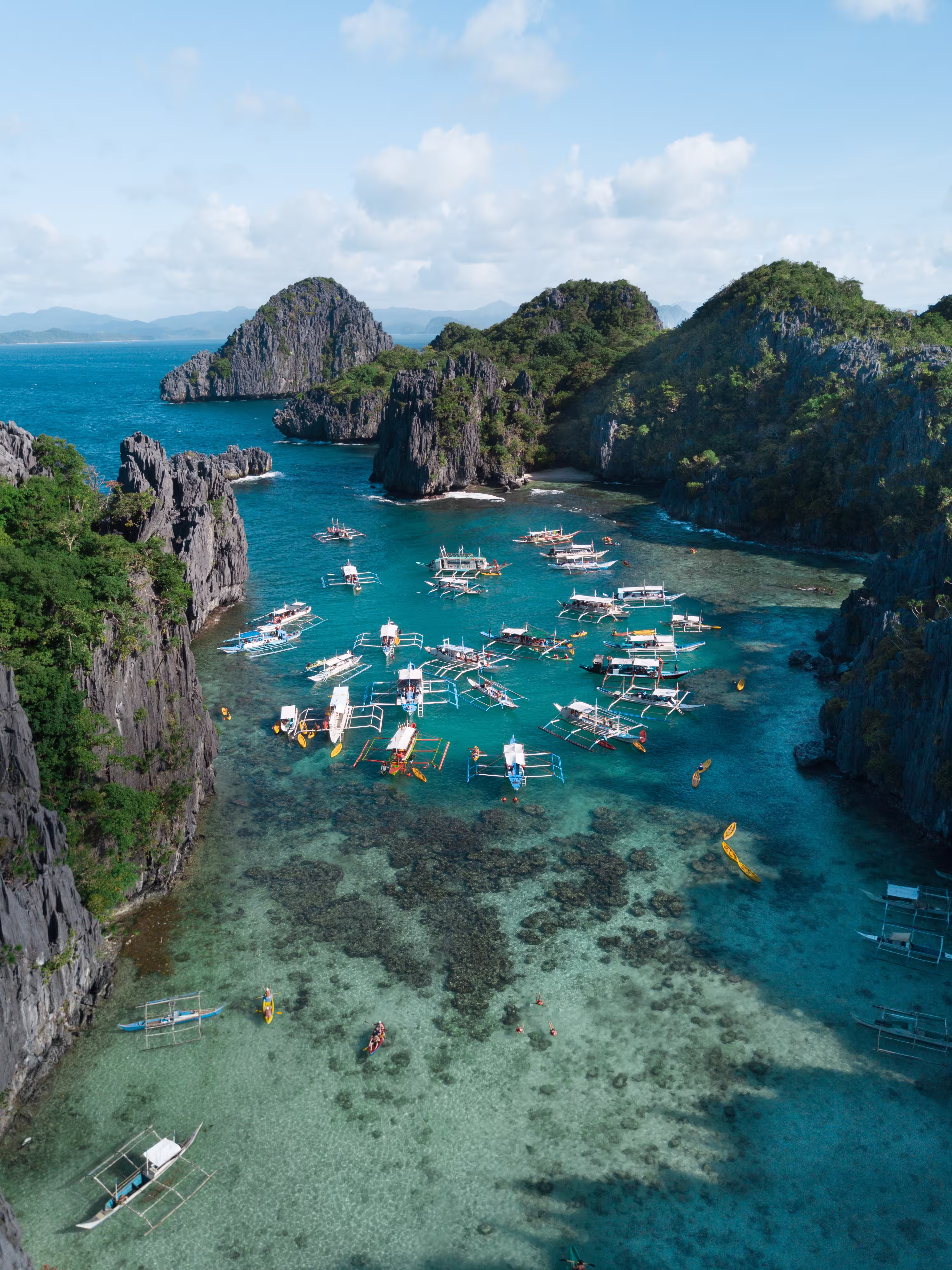 Boats on the ocean surrounded by mountains and cloudy sky