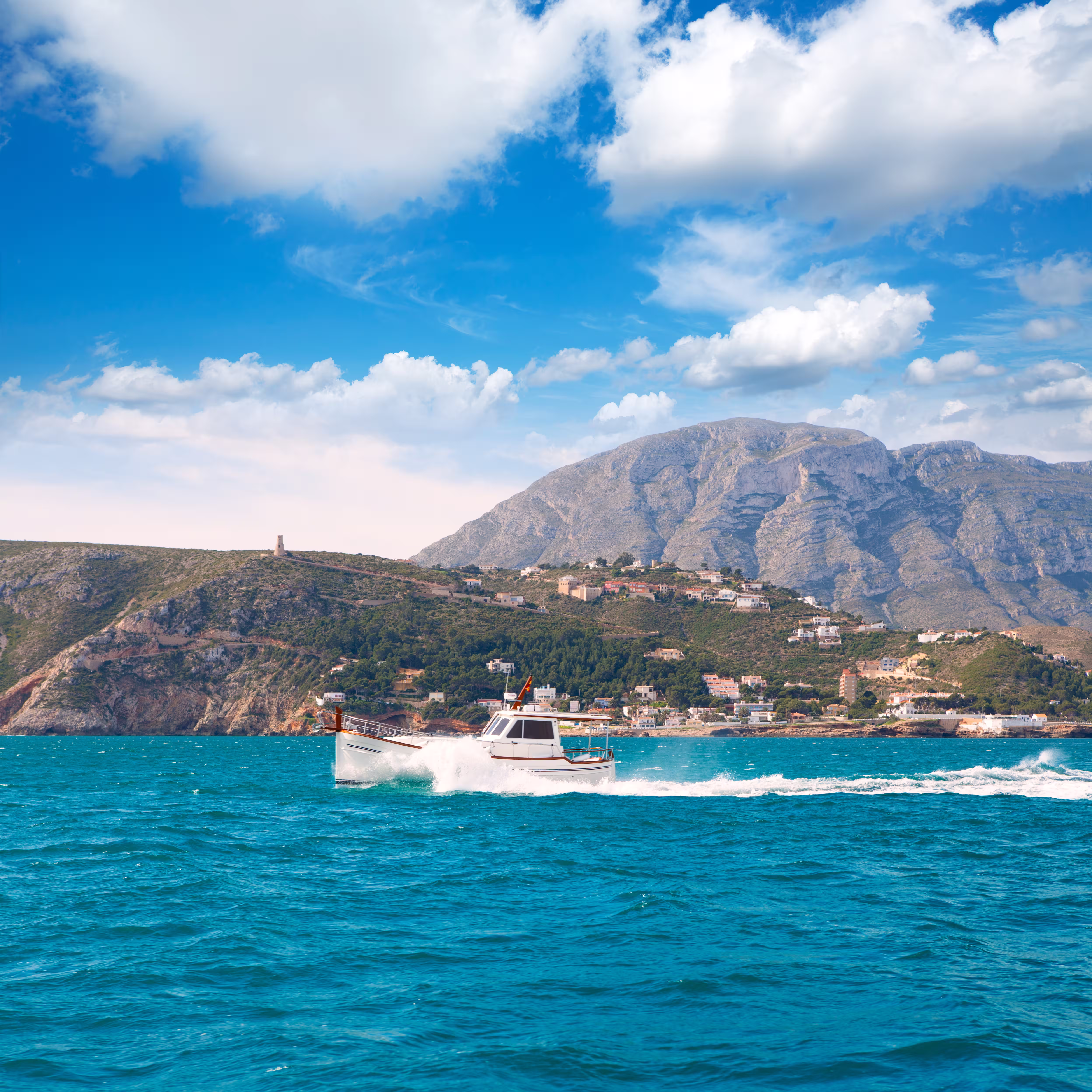 Boat sailing along a Mediterranean coastline
